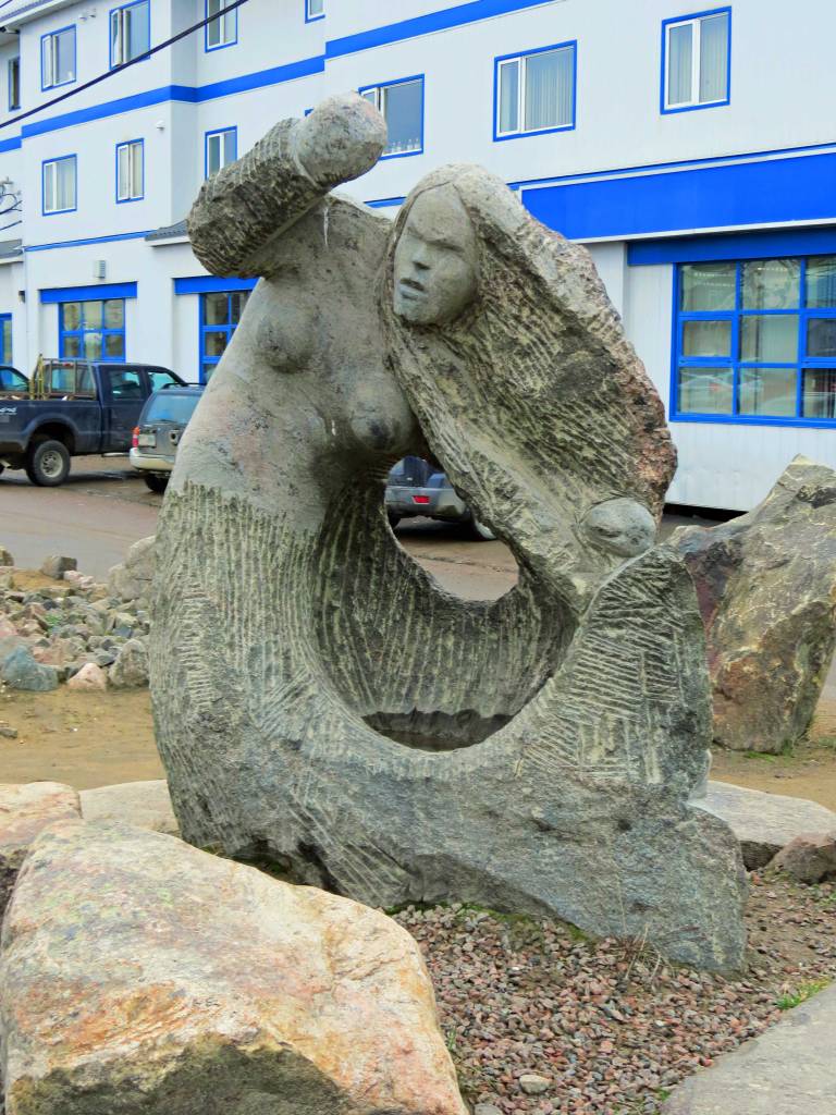 A large stone carving depicts a fingerless, angry mermaid rises up and whirls the water into waves.