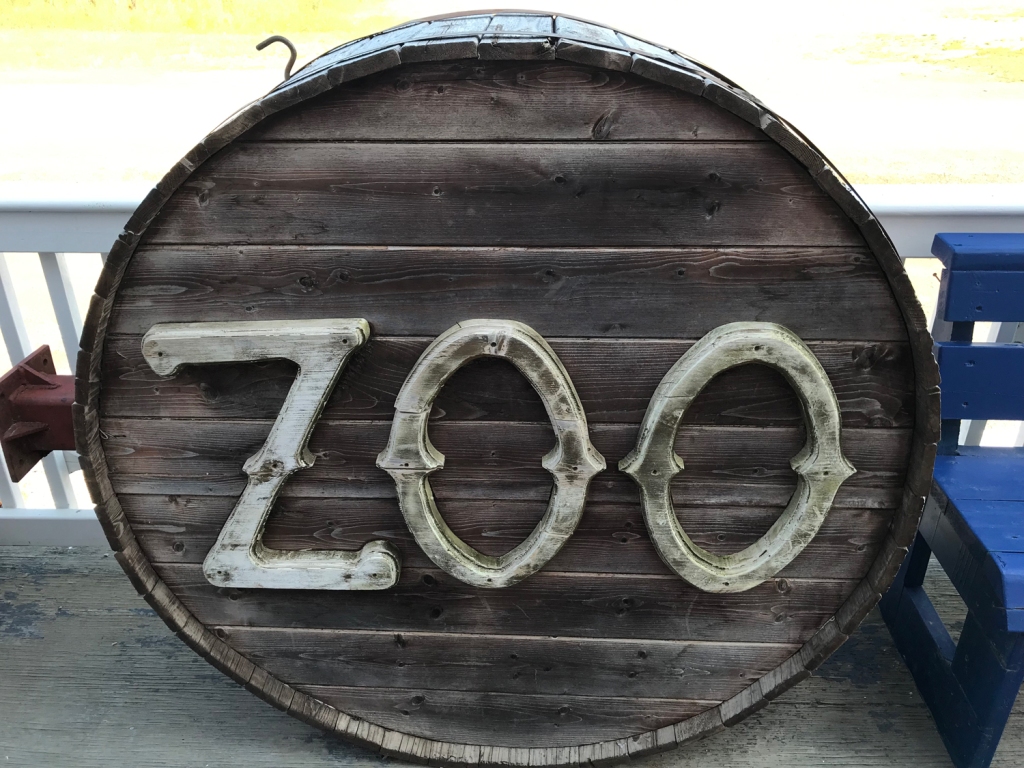 A round barrel with carved wooden letters in light grey fixed to the bottom. The letters spell out "zoo". 